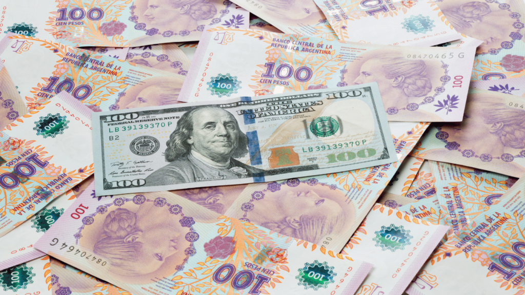 Billetes de dólar y pesos argentinos sobre una mesa, representando la relación entre el dólar y economía argentina.
