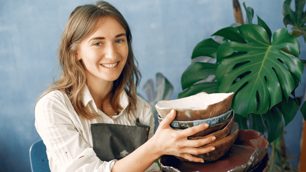 Mujer sonriente mostrando productos artesanales que hizo, representando cómo generar ingresos extras a través de la venta de productos hechos a mano en Argentina.