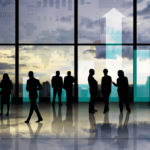 Siluetas de personas de negocios discutiendo gráficos y datos financieros frente a una ventana con vistas a una ciudad. La escena simboliza el impacto de la Inversión Extranjera Directa en el crecimiento económico y el desarrollo empresarial.