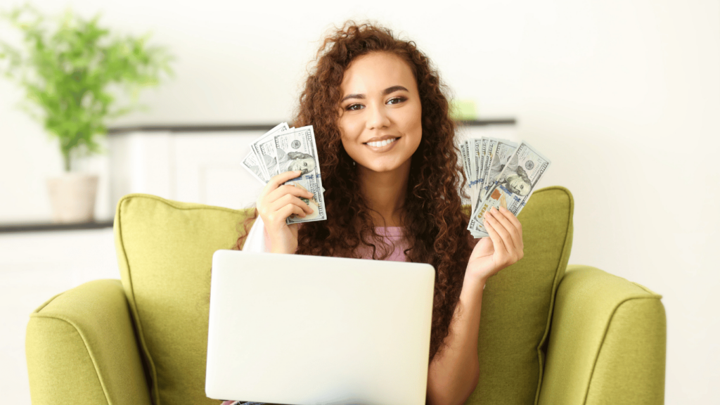 Joven sonriendo mientras sostiene billetes de dólares y usa una computadora portátil, ilustrando cómo las personas pueden invertir en el dólar Mep para ahorrar dinero en Argentina.