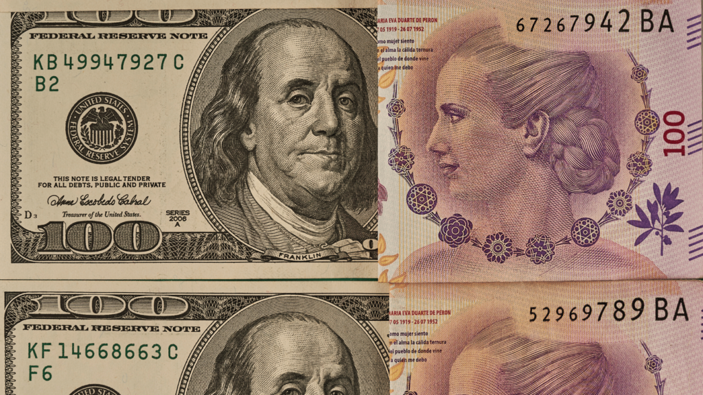 Billetes de 100 dólares estadounidenses junto a un billete de 100 pesos argentinos, representando la diferencia entre el dólar Mep y otras opciones de cambio en Argentina.