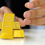 Persona manipulando lingotes de el oro como parte de una inversión física, destacando su valor y pureza.