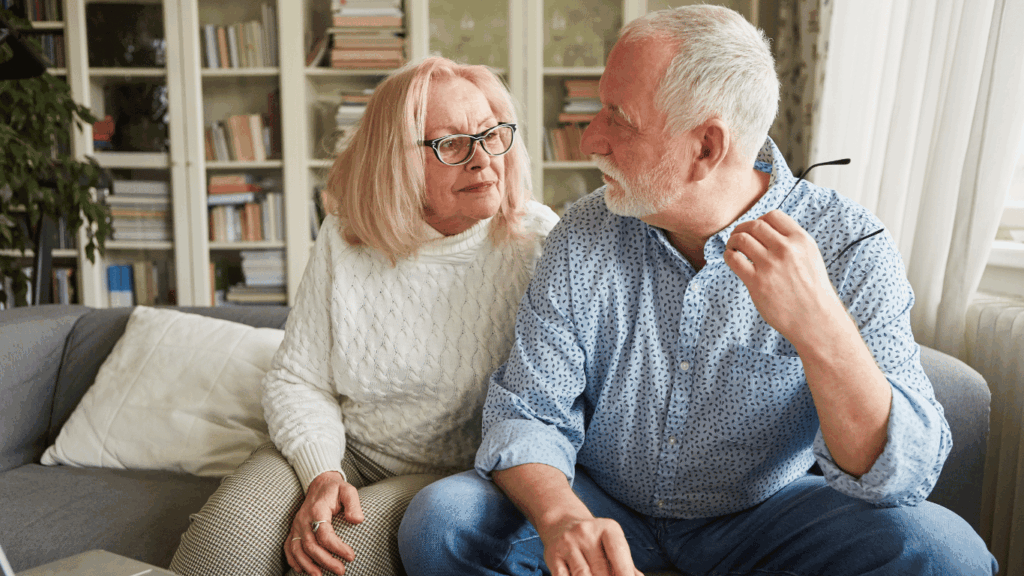 Pareja de adultos mayores conversando en su hogar, reflexionando sobre la jubilación mínima en Argentina y la planificación para el futuro financiero.