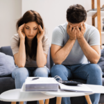 Imagen de una pareja preocupada y estresada por un préstamo atrasado en México, revisando documentos financieros en su casa.